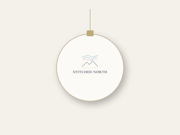 Mockup of a round white ceramic ornament with the Stitched North logo